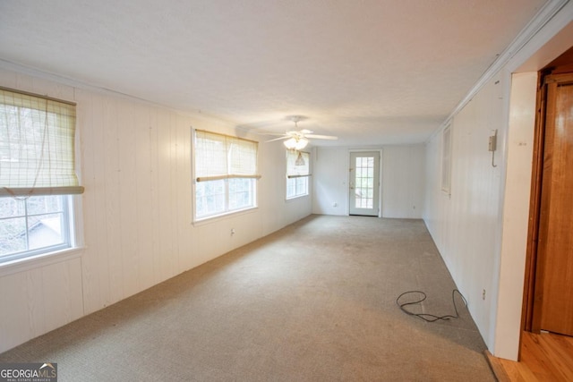 spare room with ceiling fan, ornamental molding, and light carpet