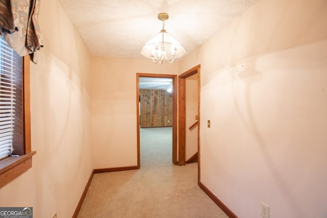 corridor featuring a textured ceiling and an inviting chandelier