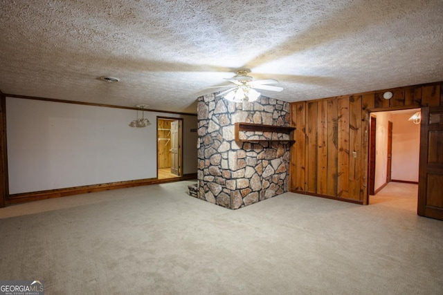 interior space featuring light carpet, a textured ceiling, crown molding, and wooden walls