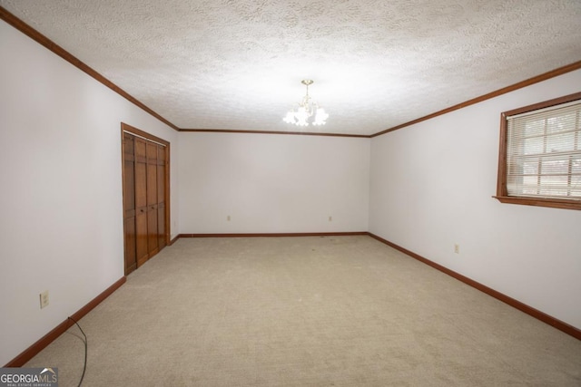 carpeted spare room with ornamental molding, a textured ceiling, and a notable chandelier