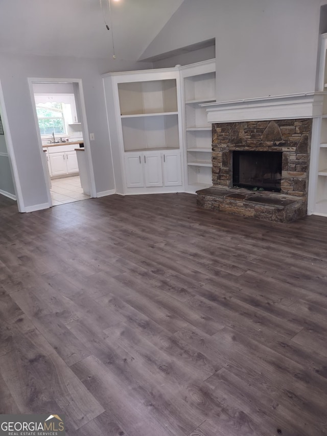 unfurnished living room with a fireplace, dark hardwood / wood-style flooring, vaulted ceiling, and built in features