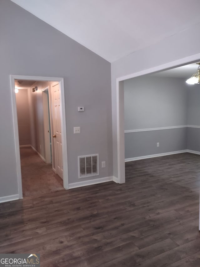 spare room with dark hardwood / wood-style floors, vaulted ceiling, and a chandelier