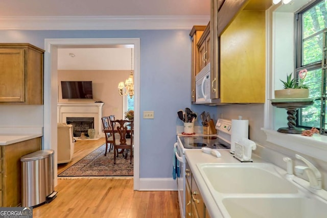 kitchen featuring white appliances, sink, light hardwood / wood-style flooring, ornamental molding, and a chandelier