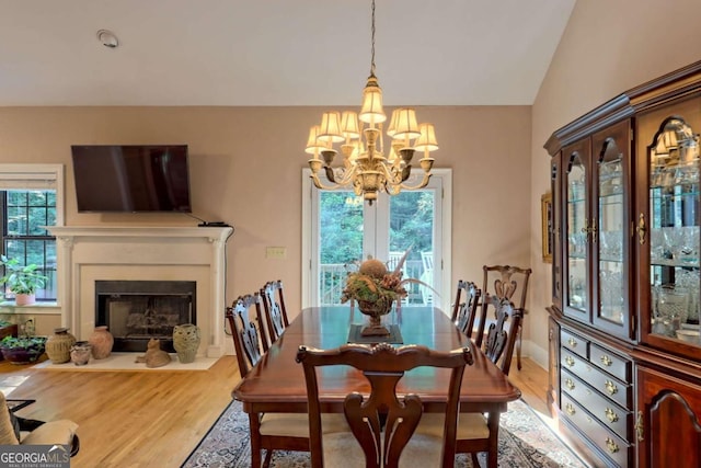 dining space featuring a notable chandelier, a healthy amount of sunlight, wood-type flooring, and vaulted ceiling