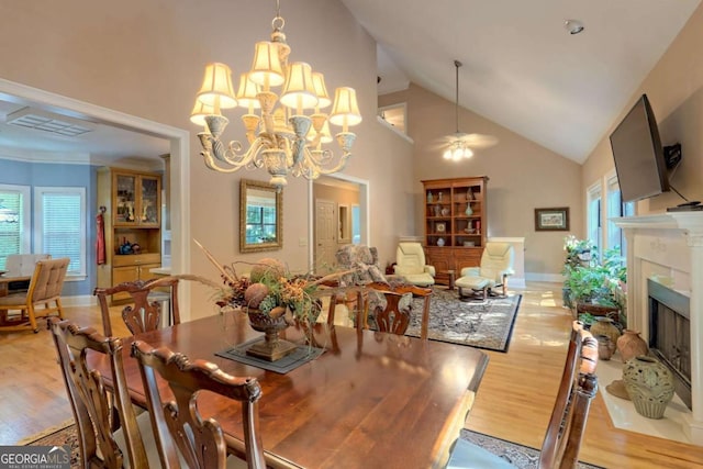 dining space featuring light hardwood / wood-style flooring, high vaulted ceiling, and ceiling fan with notable chandelier