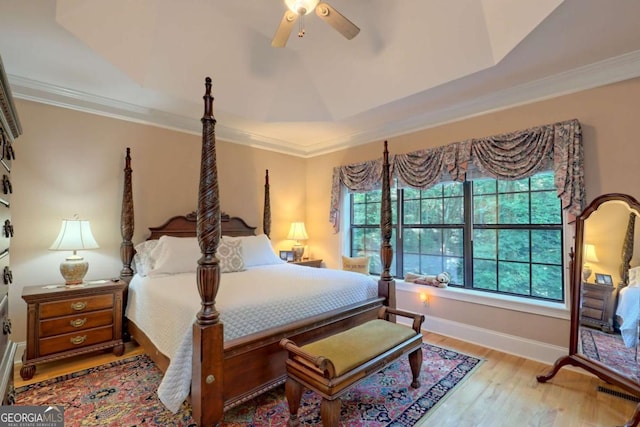 bedroom with a raised ceiling, ceiling fan, light hardwood / wood-style floors, and ornamental molding