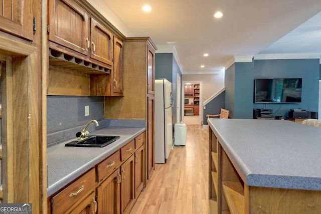 kitchen featuring sink, tasteful backsplash, light hardwood / wood-style flooring, crown molding, and white fridge