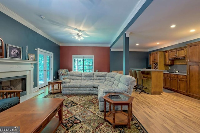 living room featuring ceiling fan, ornamental molding, and light hardwood / wood-style flooring