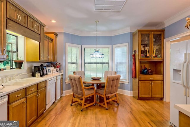 interior space featuring white appliances, sink, hanging light fixtures, light hardwood / wood-style flooring, and ornamental molding