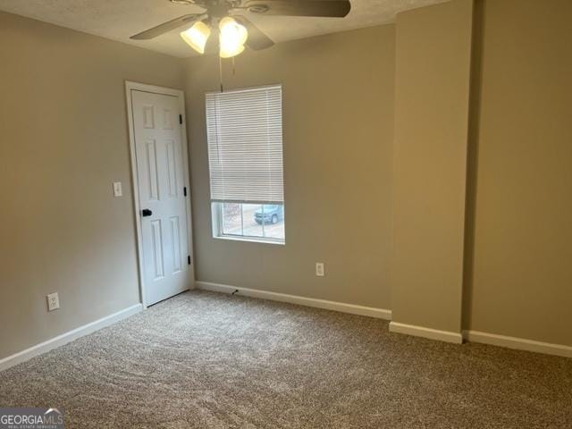 spare room with ceiling fan and carpet