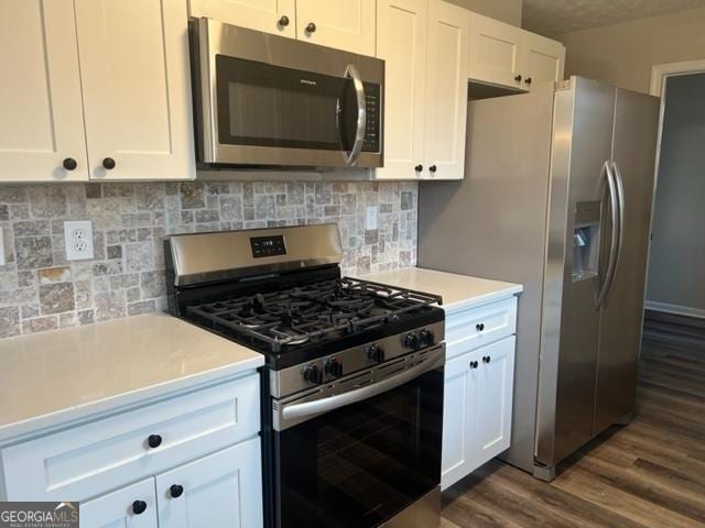 kitchen with white cabinets, backsplash, appliances with stainless steel finishes, and dark hardwood / wood-style flooring