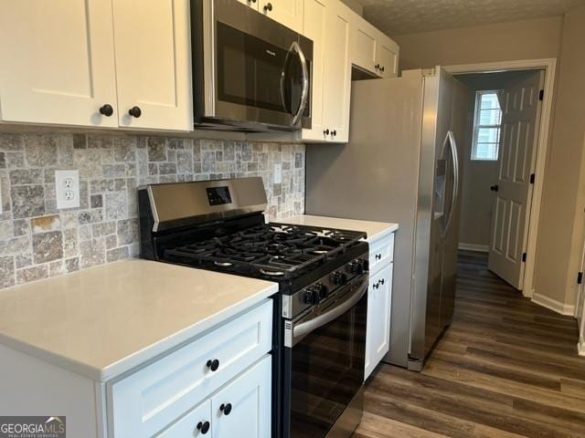 kitchen with decorative backsplash, white cabinets, dark hardwood / wood-style floors, and stainless steel appliances