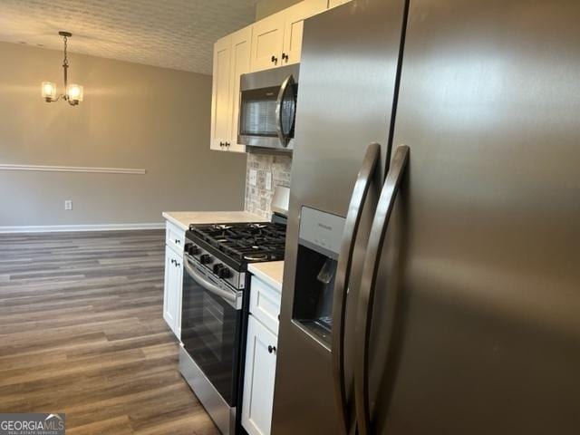 kitchen with decorative light fixtures, backsplash, stainless steel appliances, white cabinets, and a chandelier