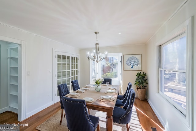 dining space featuring ornamental molding, a chandelier, and wood-type flooring