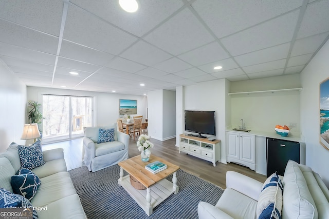 living room featuring a drop ceiling, dark hardwood / wood-style floors, and sink