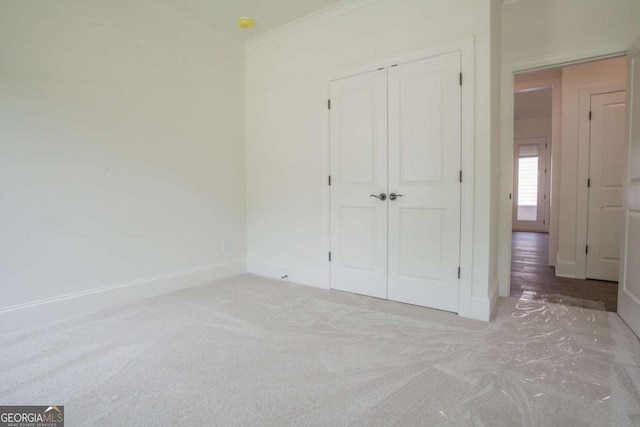 unfurnished bedroom featuring crown molding, a closet, and light carpet