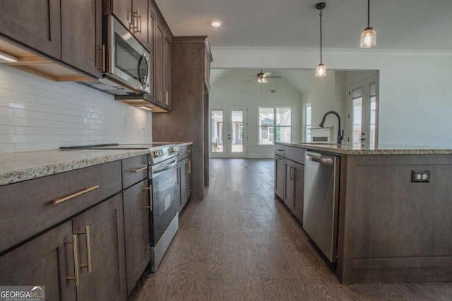 kitchen featuring french doors, a center island with sink, appliances with stainless steel finishes, tasteful backsplash, and dark brown cabinetry