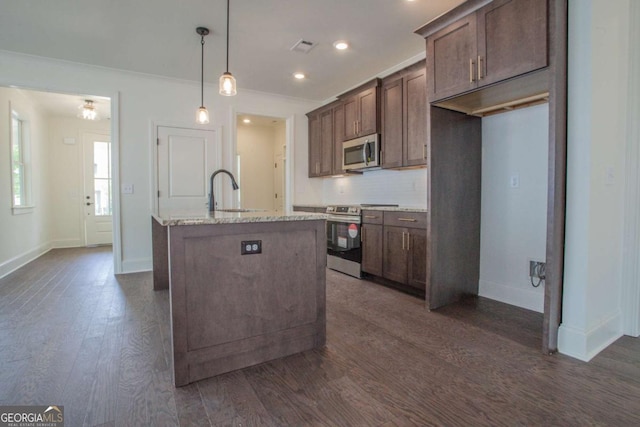 kitchen with dark wood-type flooring, light stone counters, an island with sink, pendant lighting, and appliances with stainless steel finishes