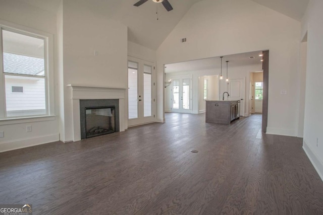 unfurnished living room featuring ceiling fan, dark hardwood / wood-style flooring, high vaulted ceiling, and sink