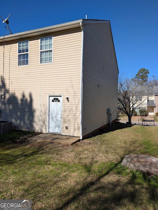 back of property featuring a lawn and central AC