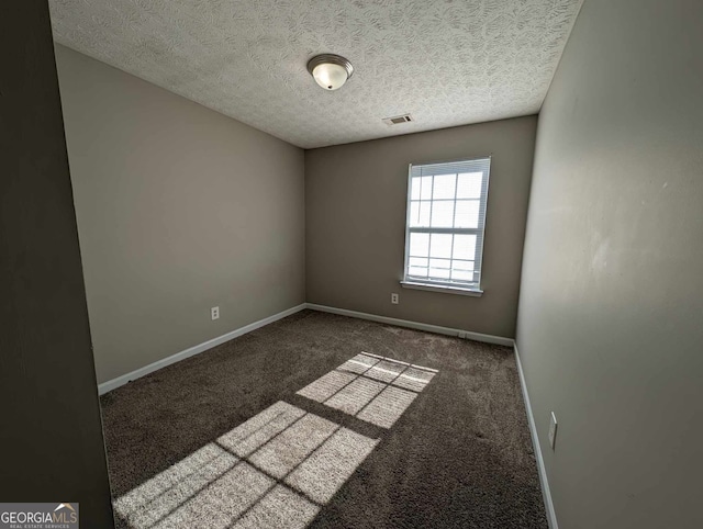 empty room with dark carpet and a textured ceiling