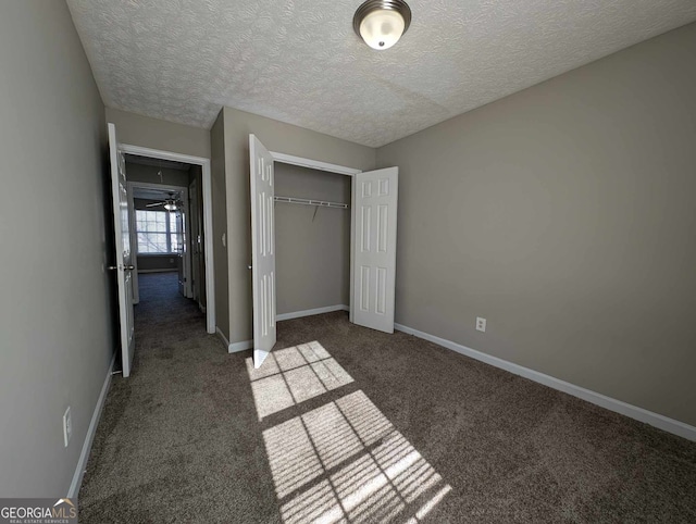 unfurnished bedroom featuring dark colored carpet, a textured ceiling, and a closet