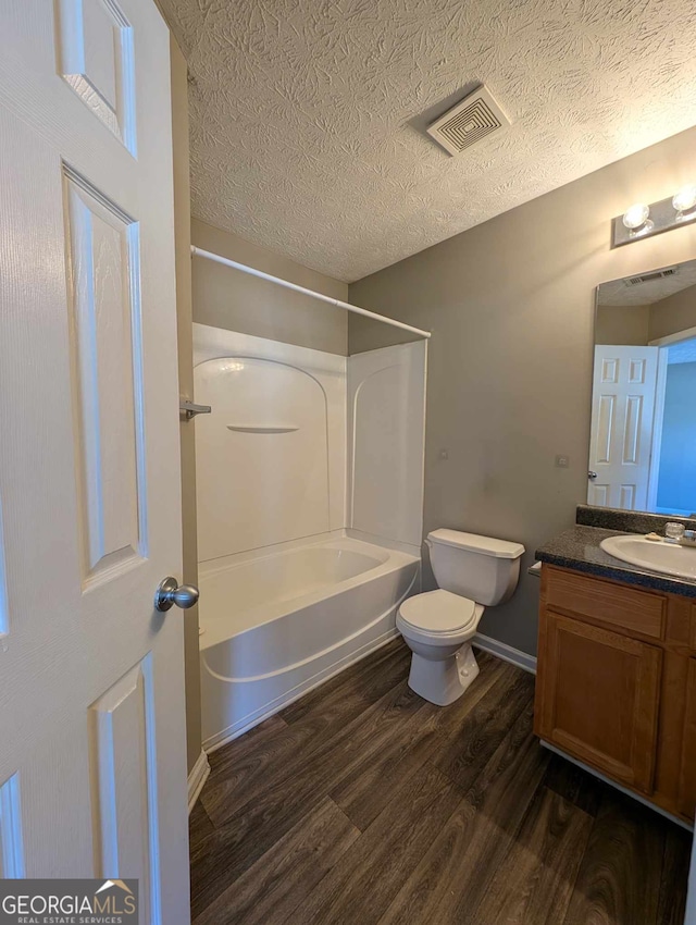 full bathroom with hardwood / wood-style floors, vanity, toilet, and a textured ceiling