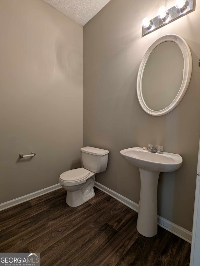 bathroom with hardwood / wood-style floors, a textured ceiling, toilet, and sink