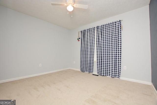 carpeted spare room with a textured ceiling and ceiling fan