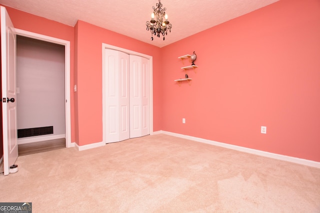 unfurnished bedroom featuring a closet, carpet, and a chandelier