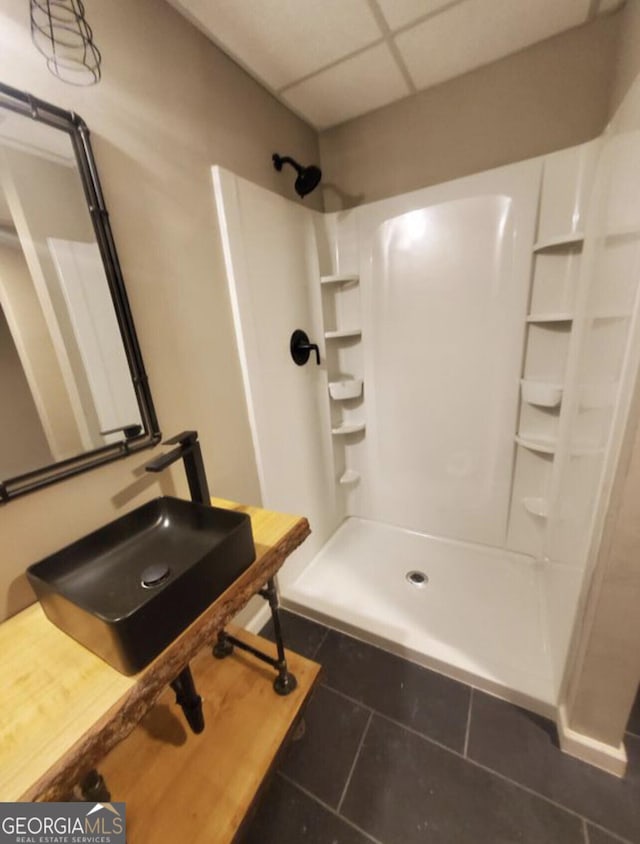 bathroom featuring a shower, tile patterned floors, a drop ceiling, and sink