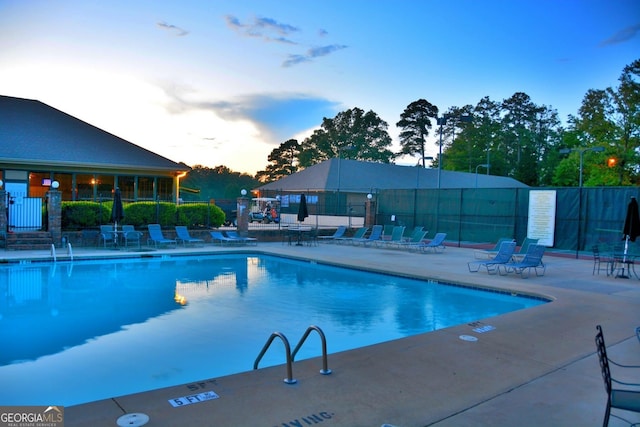 pool at dusk featuring a patio