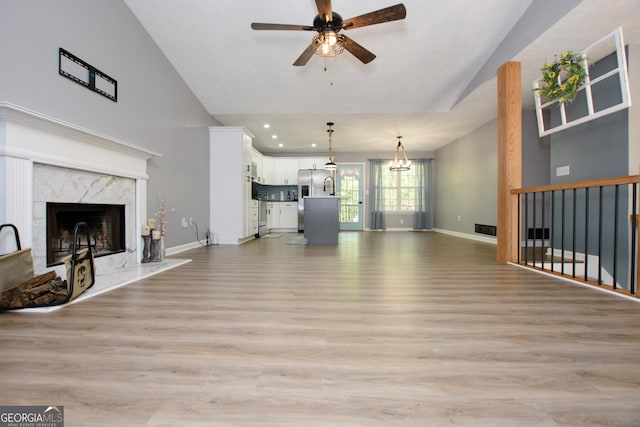 unfurnished living room featuring a high end fireplace, light hardwood / wood-style floors, and ceiling fan