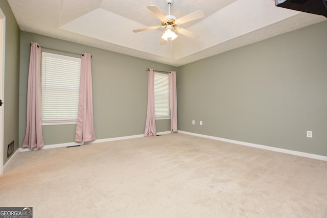 carpeted empty room featuring a textured ceiling, a raised ceiling, ceiling fan, and a healthy amount of sunlight