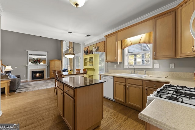 kitchen featuring decorative light fixtures, sink, a center island, white appliances, and light hardwood / wood-style flooring