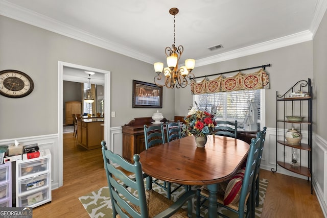 dining area featuring ornamental molding, a chandelier, and light hardwood / wood-style flooring