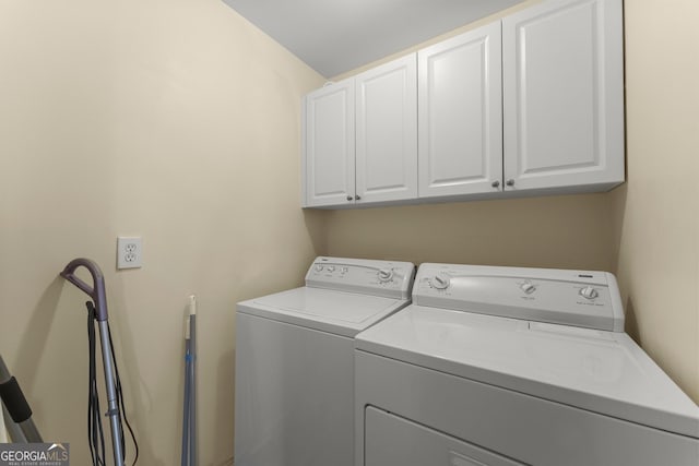 clothes washing area featuring washer and clothes dryer and cabinets