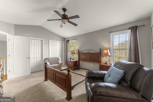 bedroom with multiple closets, lofted ceiling, light colored carpet, and ceiling fan