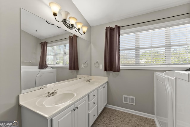 bathroom with vanity, washer / dryer, and vaulted ceiling