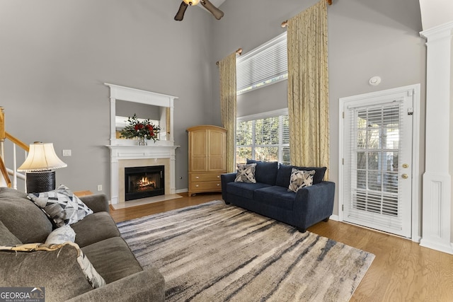 living room featuring a towering ceiling, hardwood / wood-style floors, and ceiling fan