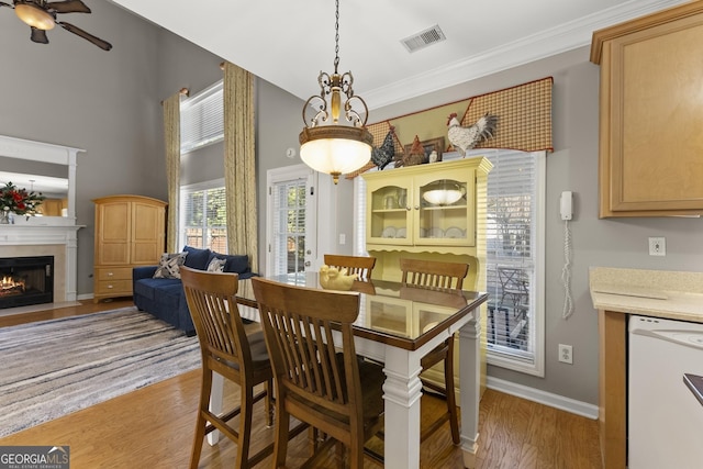 2352 Kelman Pl, Dacula, GA 30019 - dining room featuring light wood-style flooring, a ceiling fan, a fireplace with flush hearth, baseboards, and ornamental molding