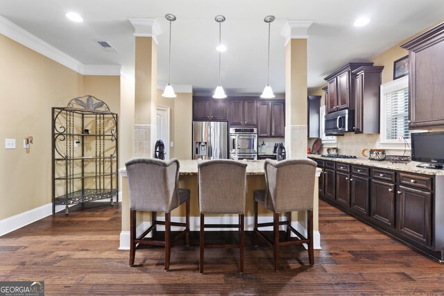 kitchen with decorative backsplash, dark hardwood / wood-style flooring, stainless steel appliances, a kitchen island, and hanging light fixtures