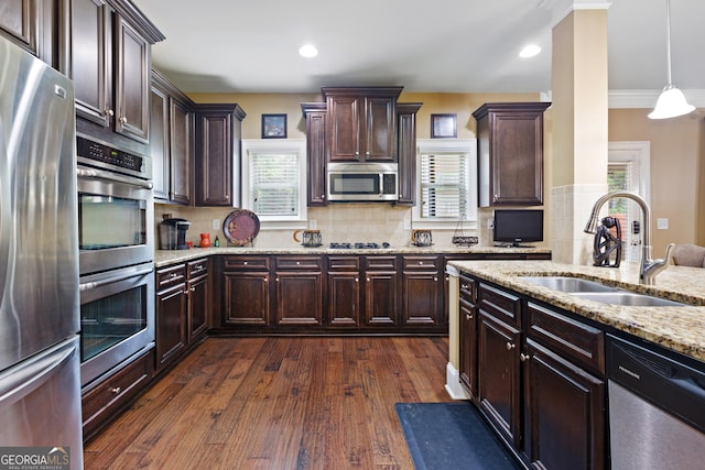 kitchen with sink, dark hardwood / wood-style floors, backsplash, pendant lighting, and appliances with stainless steel finishes