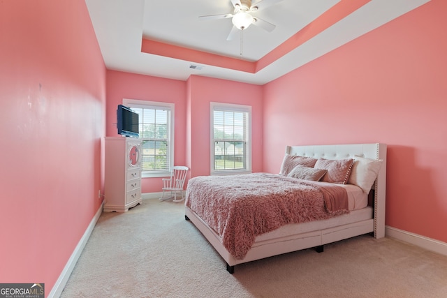 bedroom featuring light carpet, a raised ceiling, and ceiling fan