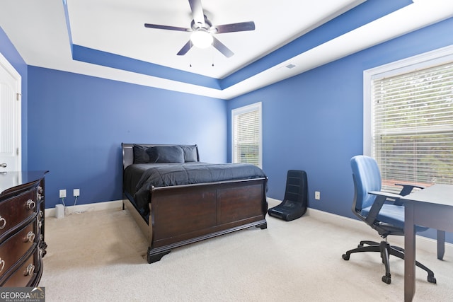 bedroom featuring ceiling fan, a raised ceiling, and multiple windows