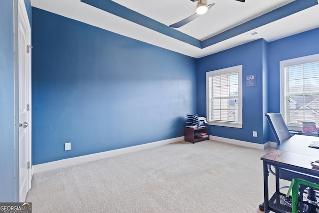 office space featuring light carpet, a raised ceiling, and ceiling fan