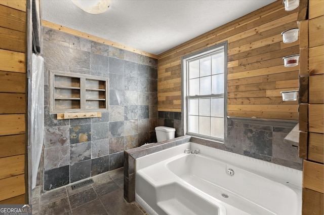 bathroom with wood walls, a bathtub, and toilet