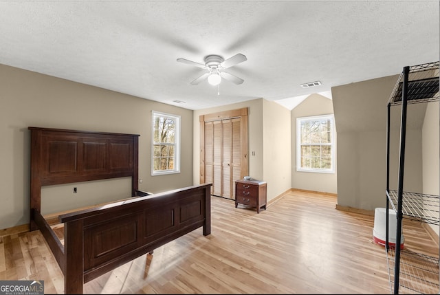 bedroom featuring ceiling fan, light hardwood / wood-style floors, and multiple windows