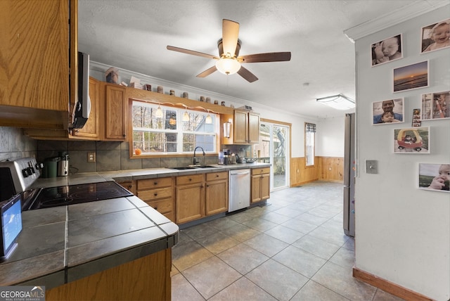 kitchen with ceiling fan, sink, stainless steel appliances, a textured ceiling, and ornamental molding