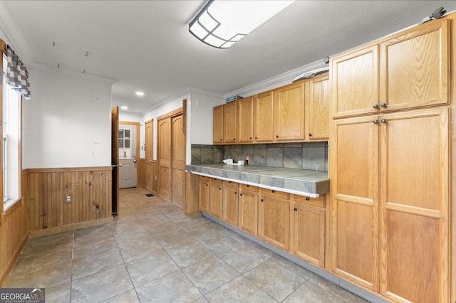 kitchen with wooden walls, crown molding, and light brown cabinetry